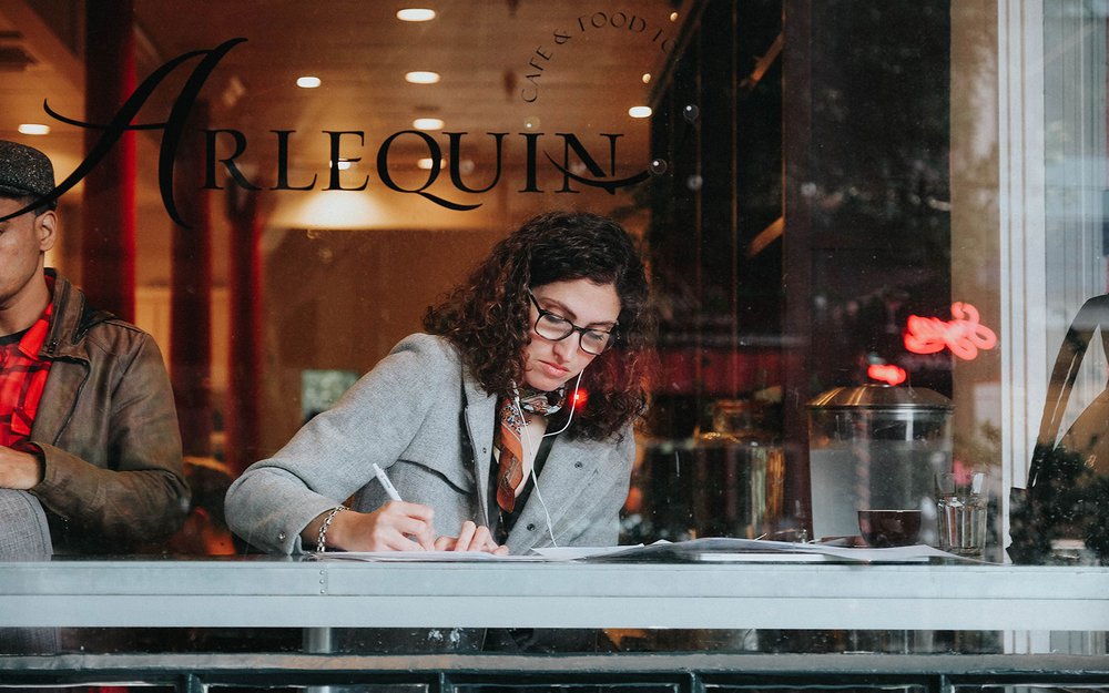 A woman sitting in a cafe and writing something on paper