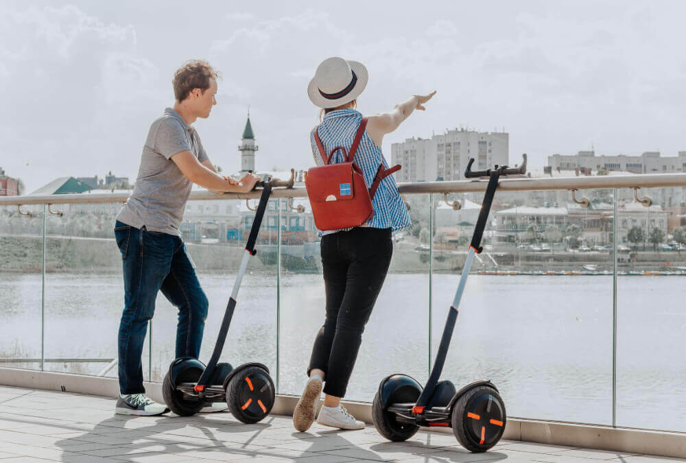 a-man-and-a-woman-riding-a-segway-on-the-river-bank